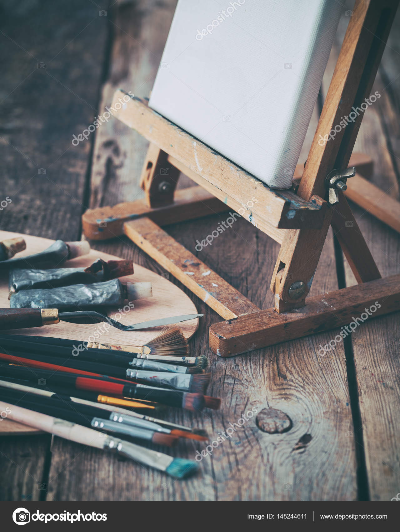 Artistic equipment: white artist canvas on easel, palette and paint brushes  in a artist studio. Retro toned. Stock Photo by ©ChamilleWhite 148244611